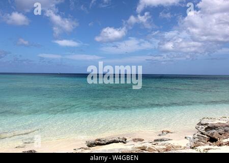 Seascape calma delle acque costiere acque blu su di una spiaggia privata nelle Isole Turks e Caicos cercando in un orizzonte nuvoloso. Foto Stock