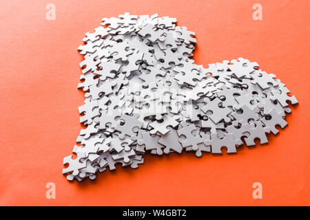 Bianco a forma di cuore puzzle di pezzi su Orange Foto Stock