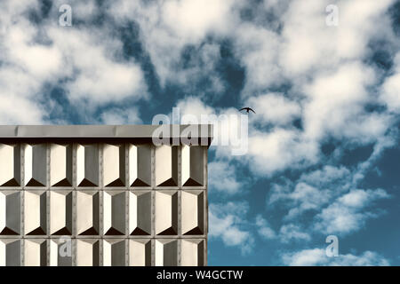 Gli uccelli del cielo con nuvole sopra un edificio urbano con una decorazione di pannelli in alluminio Foto Stock