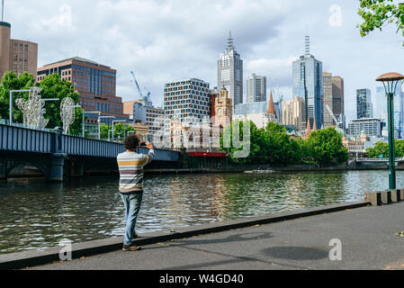 Uomo di scattare una foto del panorama urbano di Melbourne con il fiume Yarra, Victoria, Australia Foto Stock
