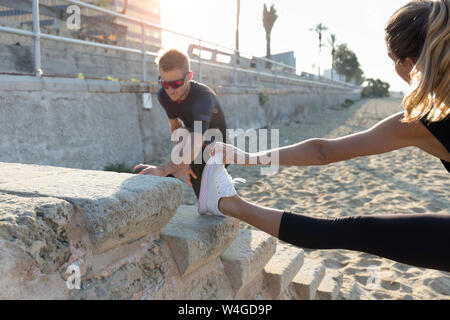 Coppia sportiva in fase di riscaldamento per la formazione sulla spiaggia Foto Stock