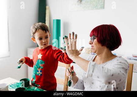 Felice madre e figlio fiving elevata mentre si fanno i mestieri a casa Foto Stock