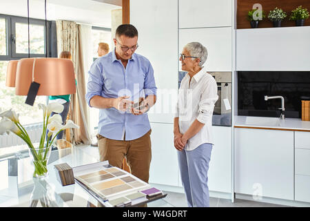 Uomo e donna matura in una cucina store esaminando campioni di materiale Foto Stock
