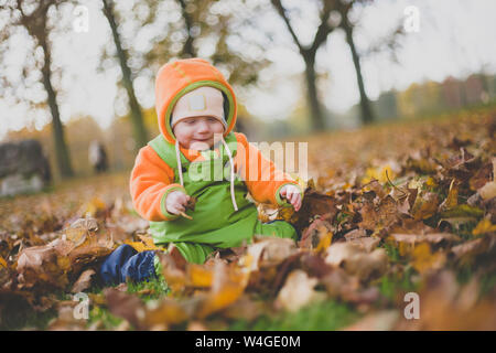 Happy Baby girl giocando in foglie di autunno Foto Stock