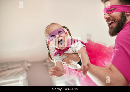 Padre e figlia gioca supereroe e superwoman, fingendo di volare Foto Stock