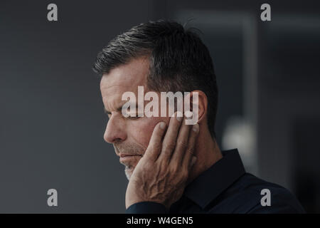 Ritratto di imprenditore maturo avente earaches Foto Stock
