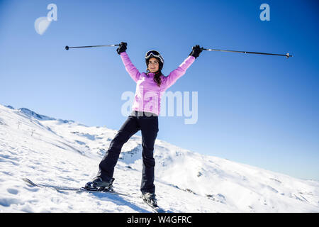 Donna felice sollevando i Suoi bastoncini da sci nel paesaggio innevato in Sierra Nevada, Andalusia, Spagna Foto Stock