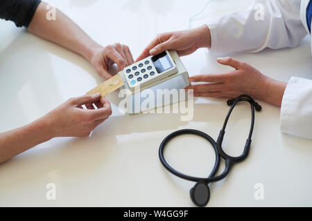 Il medico e il paziente con la carta e il lettore di schede alla pratica medica Foto Stock