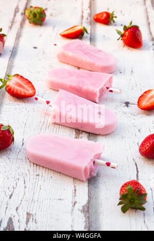 In casa di yogurt alla fragola ghiaccioli con fragole fresche in legno bianco Foto Stock