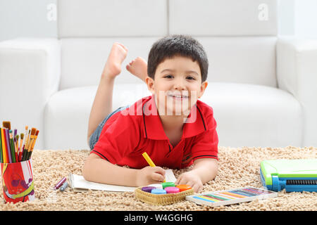 Ragazzo la colorazione di un libro e sorridente a casa Foto Stock
