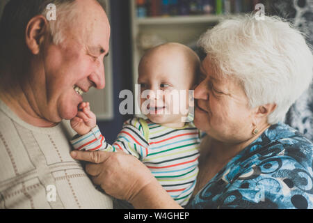 Felice nonni tenendo il loro bambino nipote Foto Stock