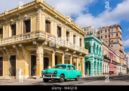 Vintage car guida nella parte anteriore di edifici coloniali, Havana, Cuba Foto Stock
