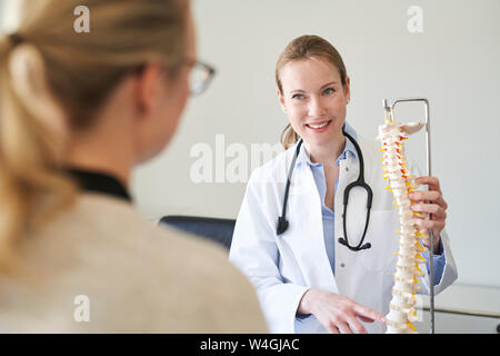 Medico donna che spiega il modello della colonna vertebrale per paziente nella pratica medica Foto Stock