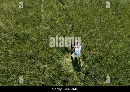 Vista aerea della sposa incinta con il marito su un prato Foto Stock