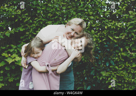 Una madre abbraccia le sue figlie Foto Stock