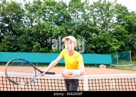 Ragazzo sul campo da tennis, in piedi presso la net Foto Stock