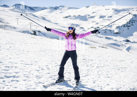 Donna felice sollevando i Suoi bastoncini da sci nel paesaggio innevato in Sierra Nevada, Andalusia, Spagna Foto Stock