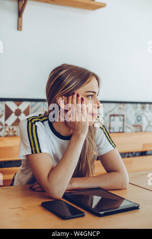 Giovane donna seduta in un bar che guarda lontano Foto Stock