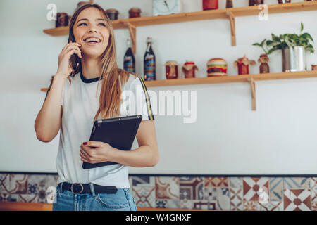Ritratto di giovane donna parla al telefono in un cafe Foto Stock