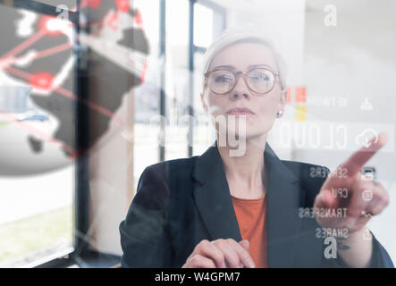 Imprenditrice di toccare la parete di vetro con dati in ufficio Foto Stock