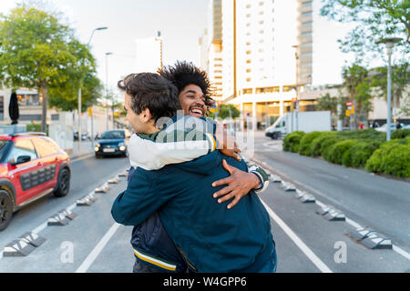 Due amici felice abbracciando nella città, Barcellona, Spagna Foto Stock