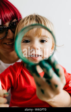 Ritratto di un sorridente bambino con sua madre attraverso un rotolo di cartone