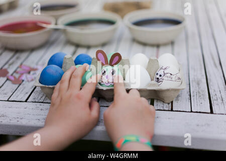 Close-up di ragazza decorazione di uovo di pasqua sul tavolo da giardino Foto Stock