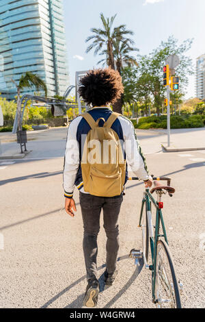 Vista posteriore del casual uomo d affari con la bicicletta in città sul andare, Barcellona, Spagna Foto Stock