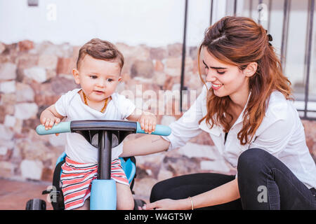 Madre con suo figlio sul triciclo Foto Stock