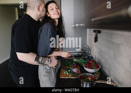 L'uomo abbracciando e baciando la donna in cucina Foto Stock
