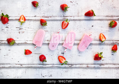 In casa di yogurt alla fragola ghiaccioli con fragole fresche in legno bianco Foto Stock