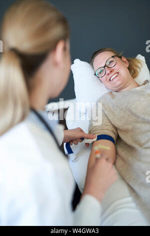 Medico donna prendendo un campione di sangue dal paziente nella pratica medica Foto Stock