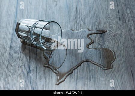 Vetro con acqua versata a trama sulla superficie di legno Foto Stock