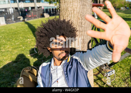 Imprenditore Casual prendendo una pausa nel parco urbano schermare gli occhi, Barcellona, Spagna Foto Stock