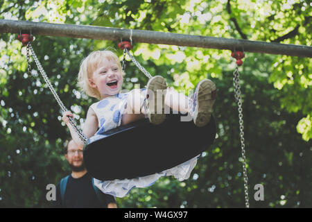 Ritratto di felice ltiitle girl su uno swing Foto Stock