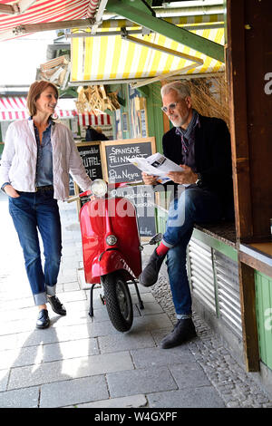 Coppia matura incontro presso il mercato, uomo raeding brochure Foto Stock