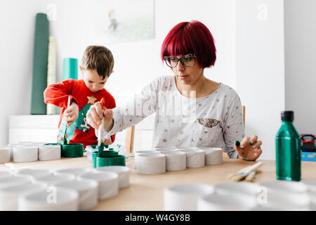 Madre e figlio fare artigianato a casa, pittura rotoli di cartone per fare un albero di Natale Foto Stock