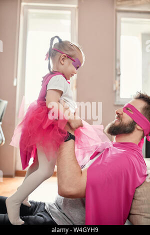 Padre e figlia gioca supereroe e superwoman, fingendo di volare Foto Stock