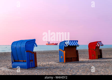 Tre incappucciati sdraio in spiaggia al tramonto, Warnemuende, Rostock, Germania Foto Stock