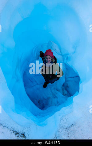 Donna in piedi in una caverna di ghiaccio, Fox Glacier, Isola del Sud, Nuova Zelanda Foto Stock