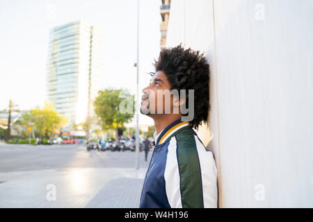 Uomo informale appoggiato contro una parete nella città, Barcellona, Spagna Foto Stock