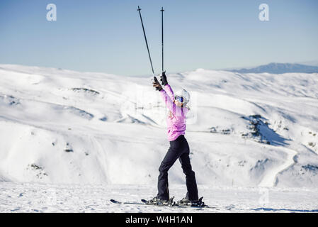 Donna felice sollevando i Suoi bastoncini da sci nel paesaggio innevato in Sierra Nevada, Andalusia, Spagna Foto Stock