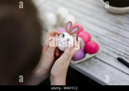 Close-up di ragazza decorazione di uovo di pasqua sul tavolo da giardino Foto Stock
