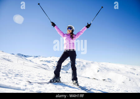 Donna felice sollevando i Suoi bastoncini da sci nel paesaggio innevato in Sierra Nevada, Andalusia, Spagna Foto Stock