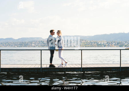 Coppia giovane in amore in piedi sul molo al Lago di Zurigo, Zurigo, Svizzera Foto Stock