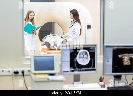 Macchina MRI e schermate con medico e infermiere. Foto Stock