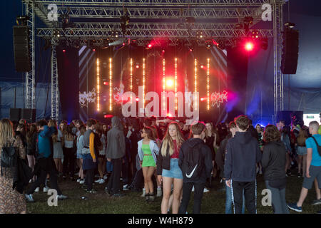 Gli adolescenti ascoltando musica rave in una grande marca in un outdoor festival di musica Foto Stock