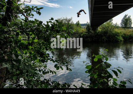 Un ragazzo adolescente backflips da una passerella nel fiume Avon a Batheaston vicino a Bath in Somerset come le temperature si elevano in tutto il Regno Unito. Foto Stock