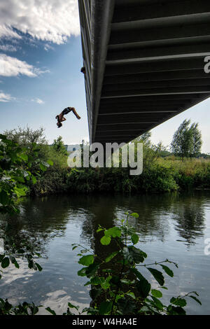 Un ragazzo adolescente backflips da una passerella nel fiume Avon a Batheaston vicino a Bath in Somerset come le temperature si elevano in tutto il Regno Unito. Foto Stock