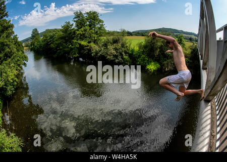 Un ragazzo adolescente salta da una passerella nel fiume Avon a Batheaston vicino a Bath in Somerset come le temperature si elevano in tutto il Regno Unito. Ondata di caldo. Foto Stock